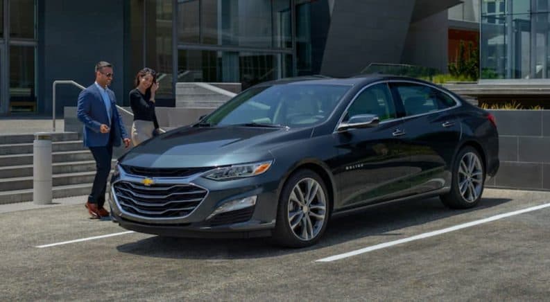 A couple is walking to a 2019 Chevy Malibu at a Chevrolet dealer.