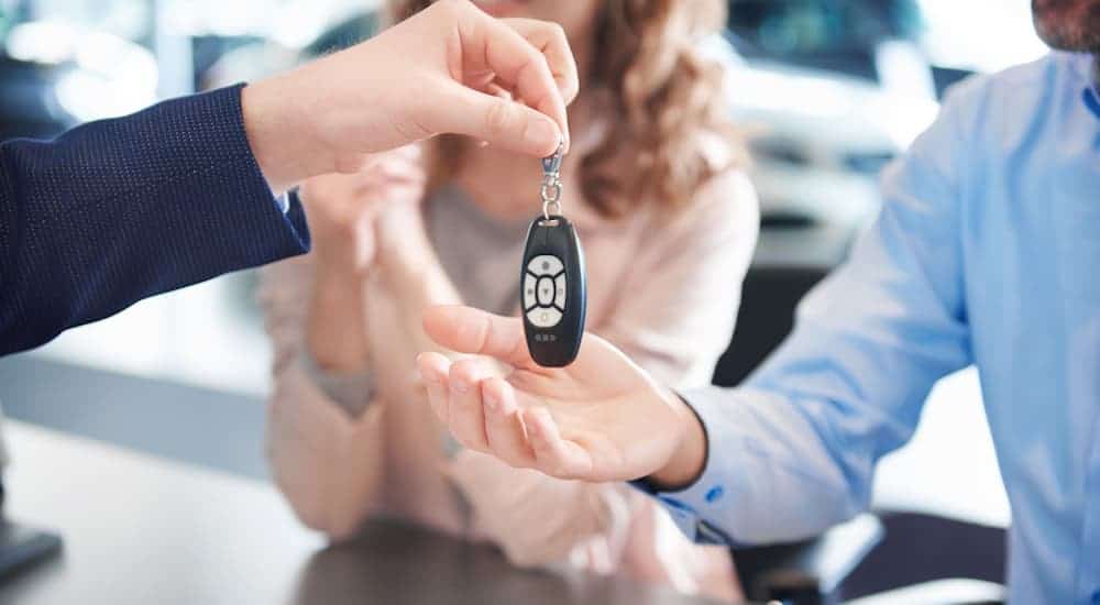 A Chevrolet dealer is handing keys to a couple in a closeup.