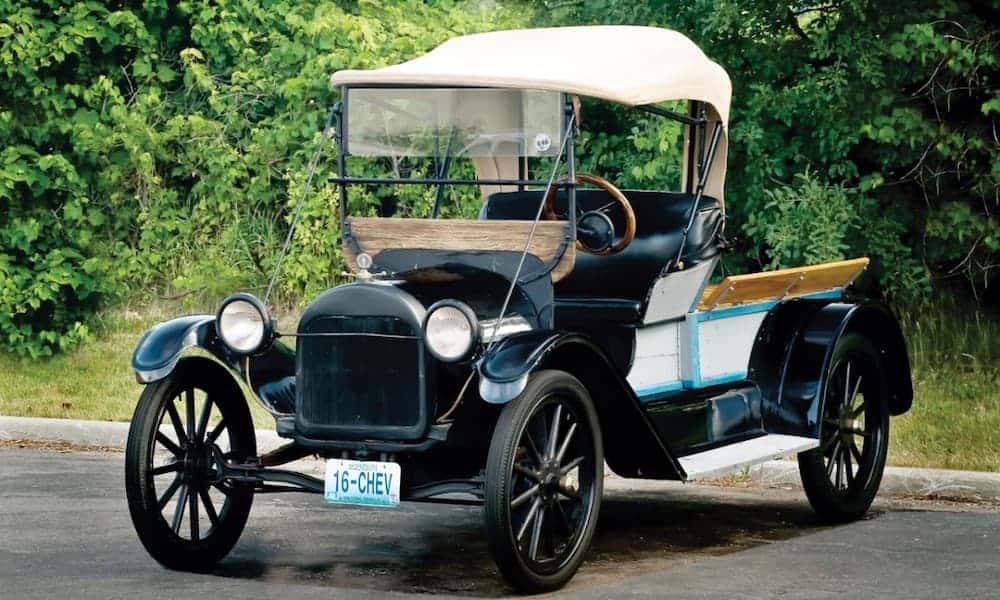 A black 1916 Chevrolet Series 490 is shown in front of trees.