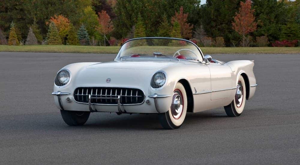 A silver 1953 Chevy Corvette is in an open parking lot.