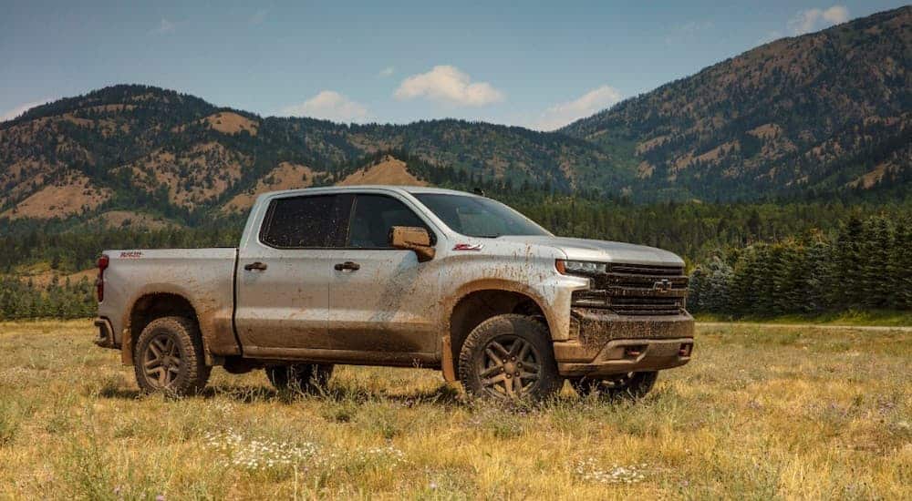 A muddy 2019 Chevrolet Silverado TrailBoss is parked in front of mountains.