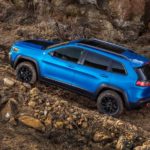 A blue 2019 Jeep Cherokee is climbing a rocky trail.