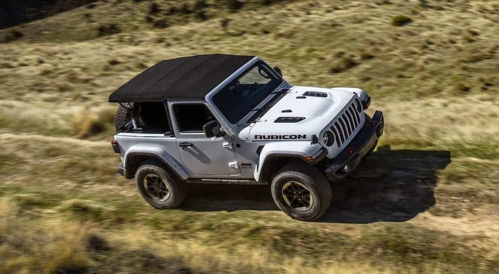 A white 2019 Jeep Rangler Rubicon is driving off raod in a field after leaving a Jeep dealership near Dallas.