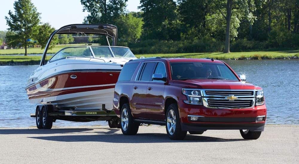 A red 2015 Chevy Suburban is pulling a boat out of the water.