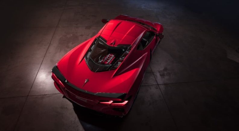 A red 2020 Chevy Corvette is shown from above in a dark room.