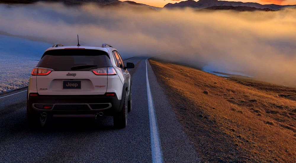 A white 2019 Jeep Cherokee is driving towards fog after leaving a Jeep dealership near me.