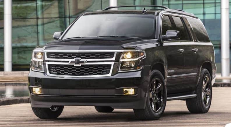A black 2020 Chevy Suburban is parked in front of glass windows.