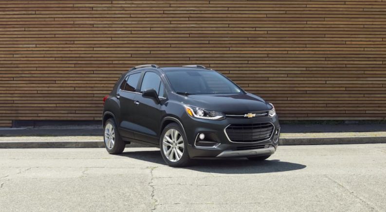 A grey 2020 Chevy Trax is parked in front of a wood wall.