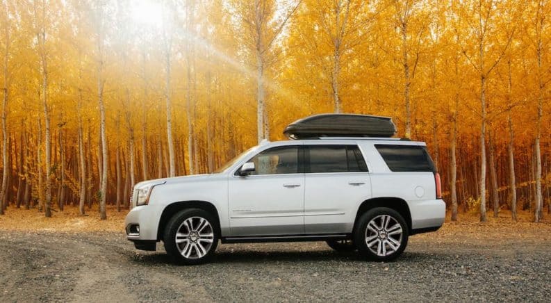 A white 2020 GMC Yukon is parked in front of Fall foliage.