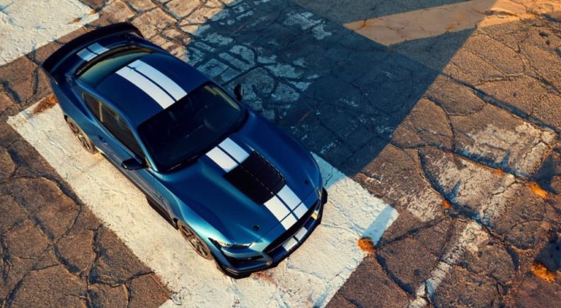 A blue 2020 Shelby GT500 with white stripes is on an old race track.