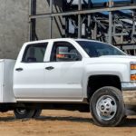 A white utility bed 2018 Chevy 3500 Chasis Cab, popular among diesel trucks for sale, is at a construction site.