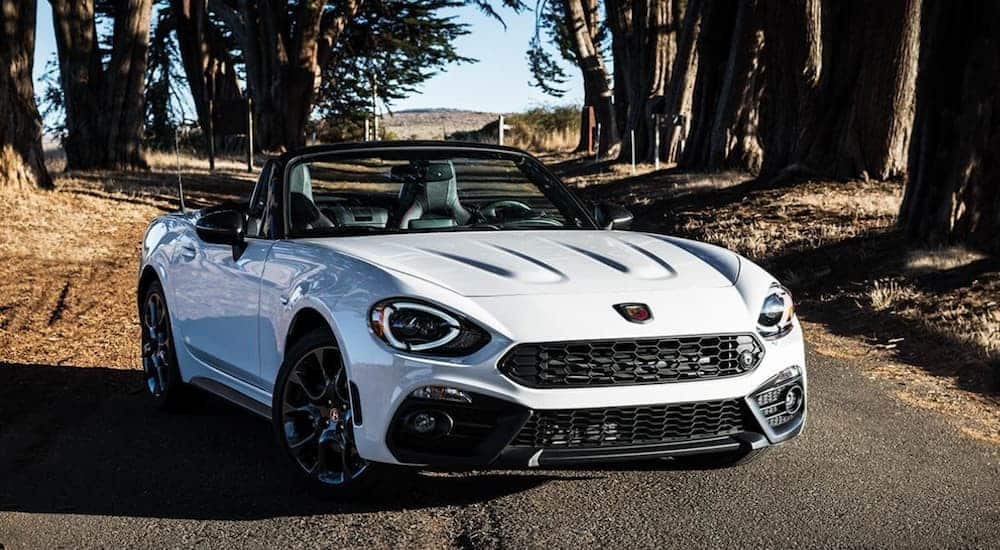 A white 2019 Fiat 124 Spider Sport is parked with trees in the background. 