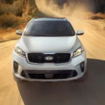A white 2019 Kia Sorento is driving on a dirt road.