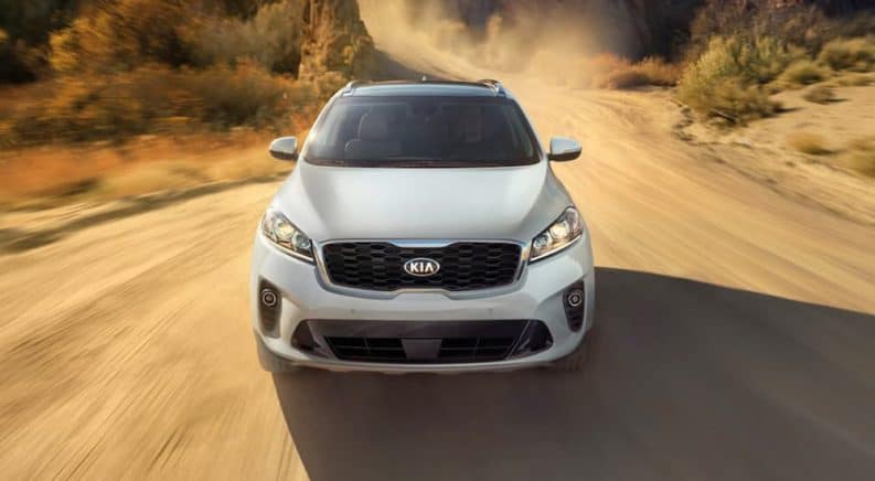 A white 2019 Kia Sorento is driving on a dirt road.