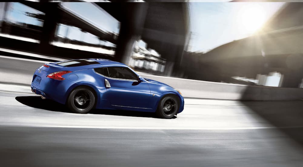 A blue 2016 used Nissan 370z is driving on a highway system.