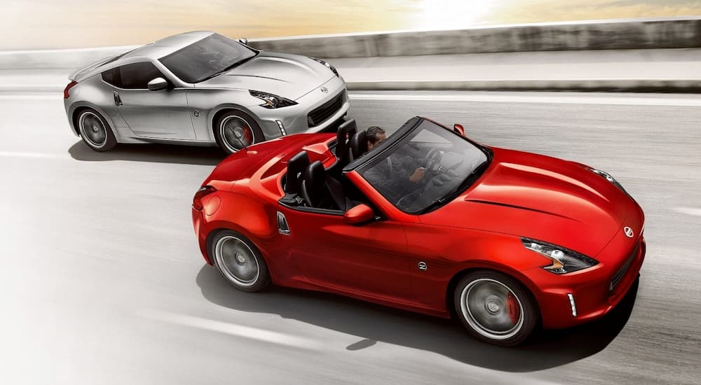 A red 2019 used Nissan 370z Roadster is driving in front of a silver coupe.