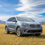 A silver 2020 Kia Sorento is parked in a grassy field on a bright sunny day.
