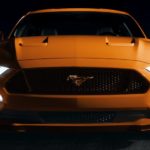 The front end of an orange 2020 Ford Mustang in shown.