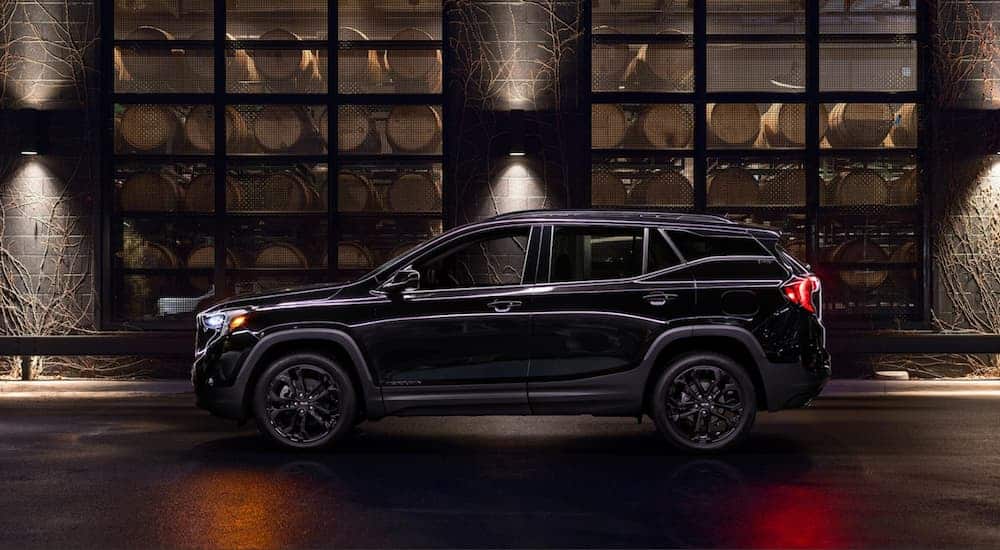 A black 2019 GMC Terrain, which wins when comparing the 2019 GMC Terrain vs 2019 Honda CR-V, is parked on a dark side street at night. 