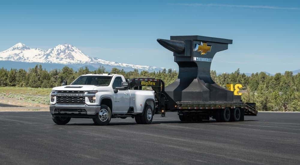 A white 2020 Chevy Silverado 3500HD, which you can find at a local Chevy dealer, is towing a large piece of steel with a gooseneck.