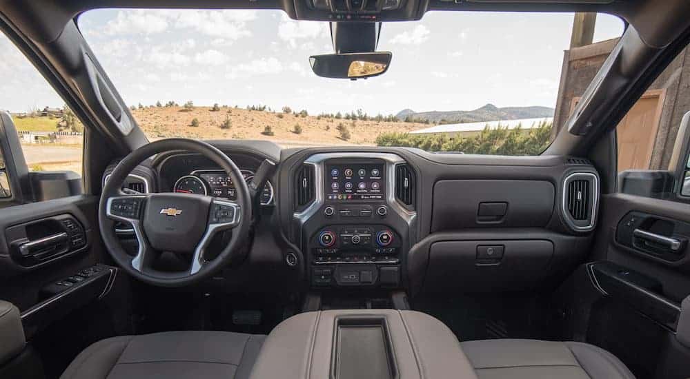 A front view of the black and grey leather interior of a 2020 Chevy Silverado HD is shown with an infotainment system. 