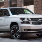 A white 2020 Chevy Tahoe is parked on a dark city street.