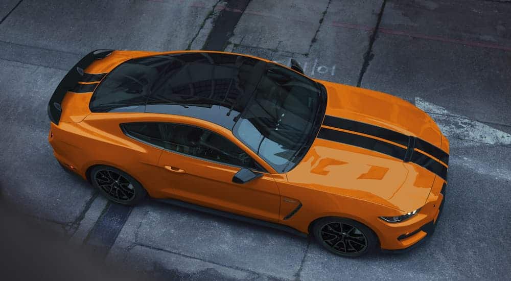  A birds eye view of an orange 2020 Ford Mustang Shelby GT350 with a black racing stripe is parked in an ally.