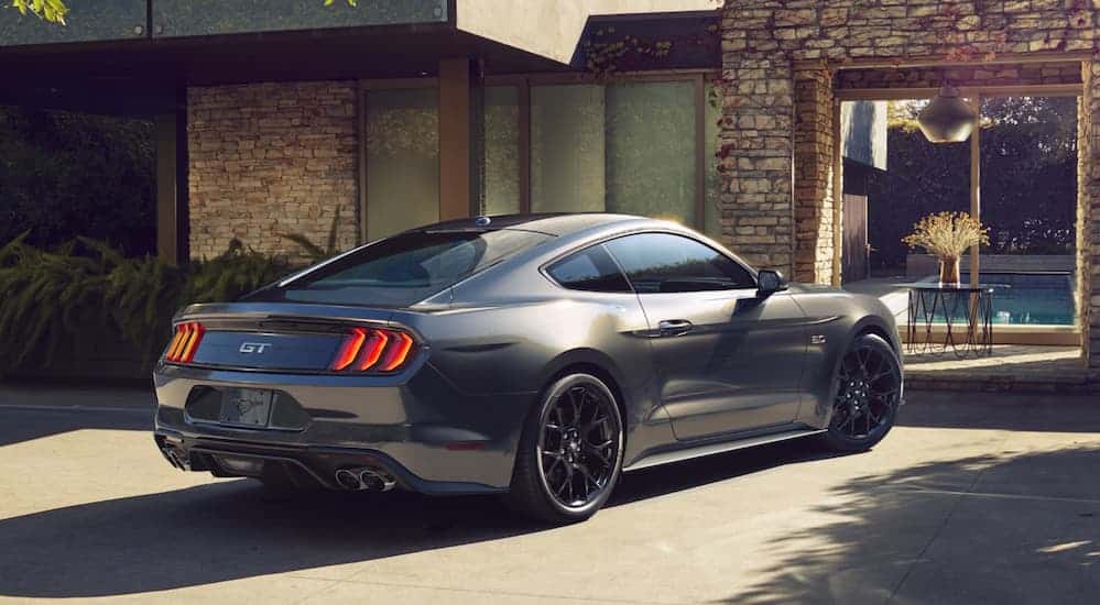 A grey 2020 Ford Mustang GT is parked in a driveway in front of a house. 