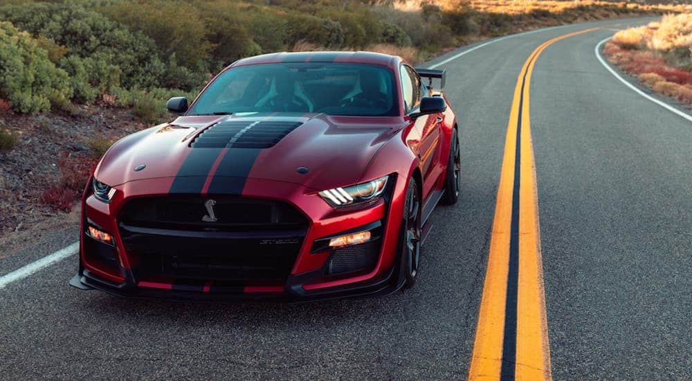 A red 2020 Ford Mustang GT500 is driving down a road in the desert.