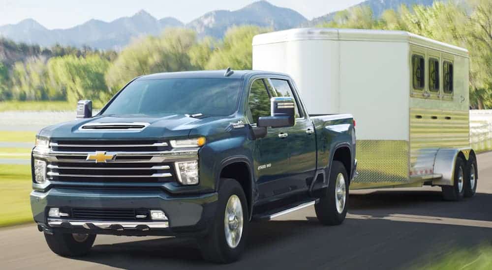 A blue 2020 Chevy Silverado HD is towing a large horse trailer