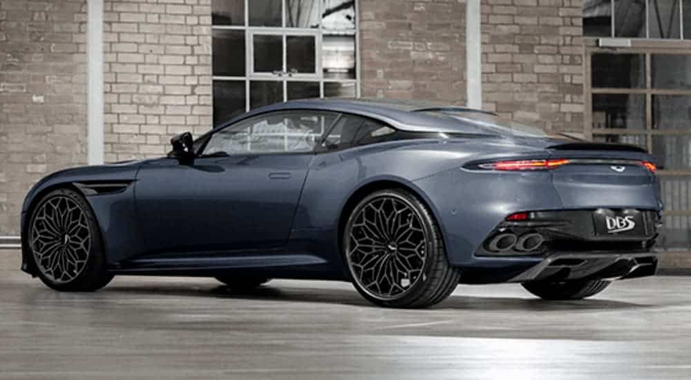 The 007 Aston Martin DBS Superleggera is shown from the rear in a room with brick walls and is popular in current auto news at the moment.