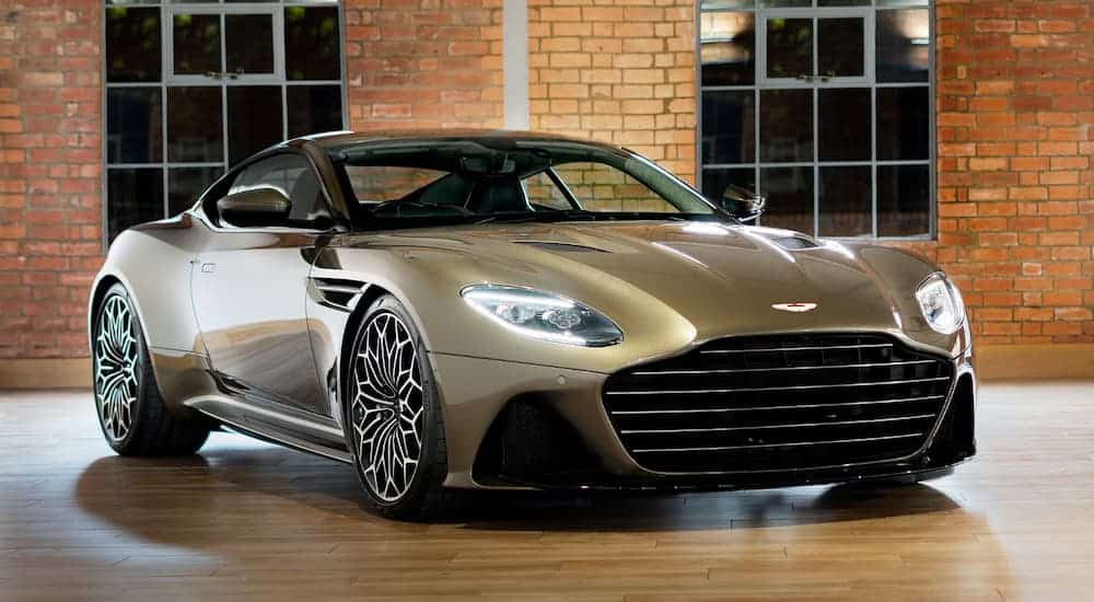 The 007 Aston Martin DBS Superleggera is in front of a brick wall and windows.