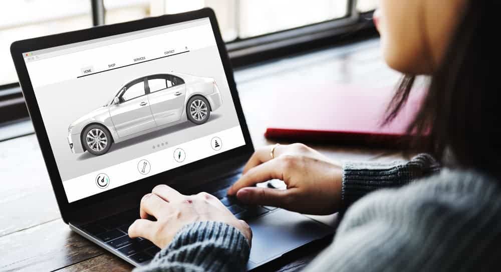 After reading online car shopping tips, a woman is searching for her dream car on her laptop.