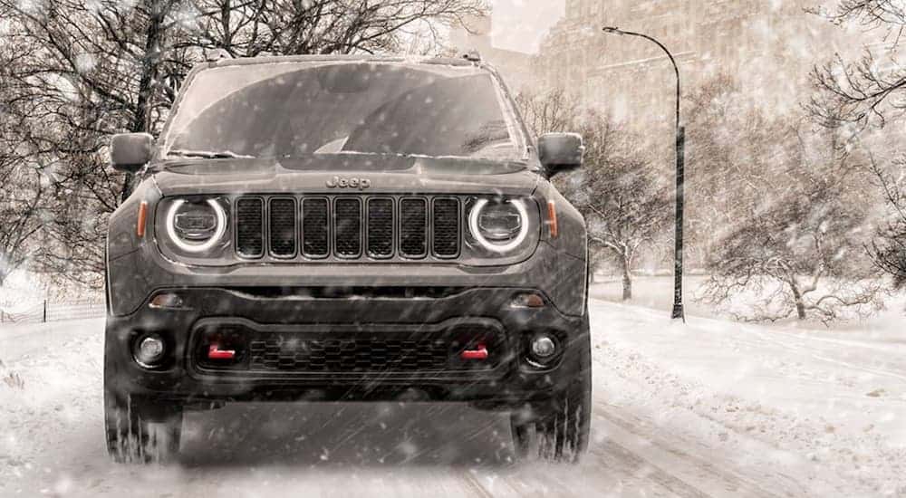 A grey 2020 Jeep Renegade, which wins when comparing the The 2020 Jeep Renegade vs the 2020 Hyundai Kona, is driving on a snow covered road during a snow storm.