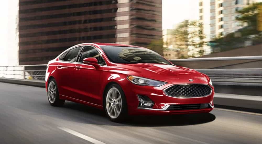 A red 2020 Ford Fusion is driving on a highway. 