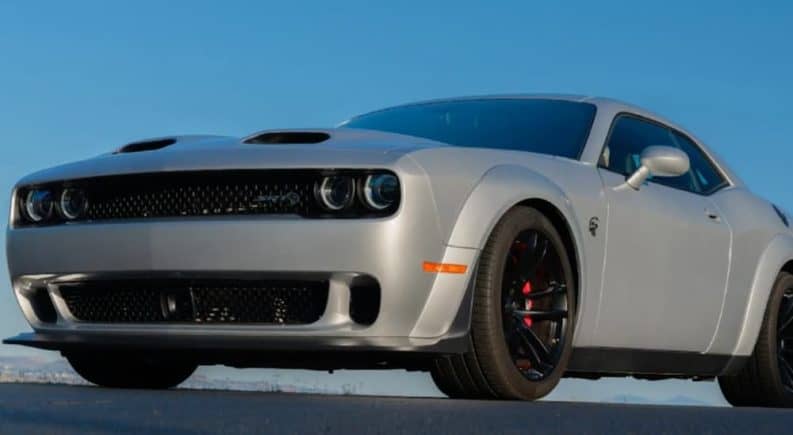 A grey 2019 Challenger Hellcat is parked in an empty parking lot with a blue sky.
