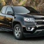 A black 2020 Chevy Colorado is driving on a road past a sharp corner.
