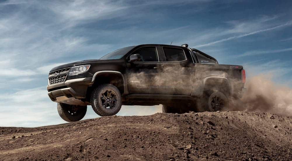 A black 2020 Chevy Colorado ZR2 is jumping a dirt mound.