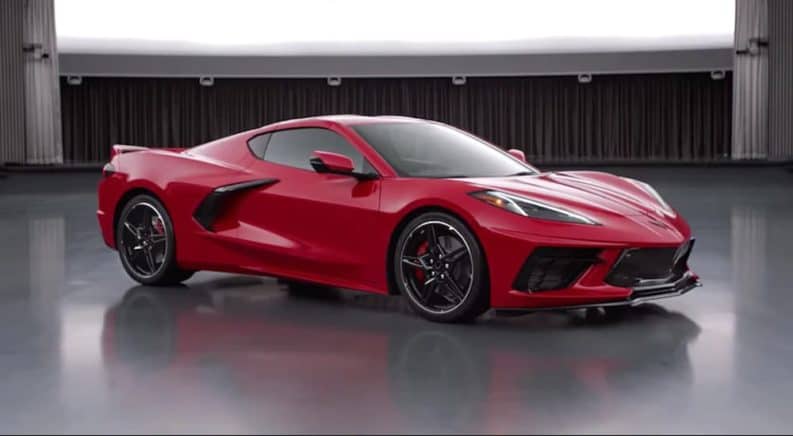 A red 2020 Chevy Corvette is parked in an empty grey showroom.
