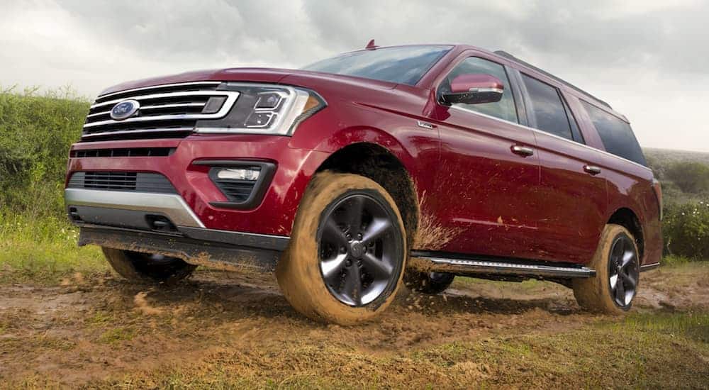 A red 2020 Ford Expedition has mud on the front fenders while driving on a muddy trail.