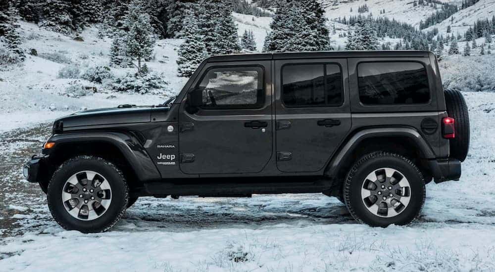 A side view of a grey 2020 Jeep Wrangler Sahara Edition 4-door is shown parked on a snow covered ground.