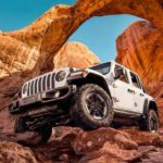 A white 2020 Jeep Wrangler, which wins when comparing the 2020 Jeep Wrangler vs 2020 Jeep Gladiator, is off-roading in a red rocks canyon.