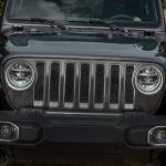 A close up of a grey 2020 Jeep Wrangler JL is driving through the mud.