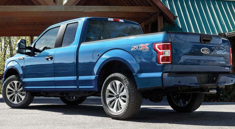 A blue 2020 Ford F-150 is parked facing a house. 