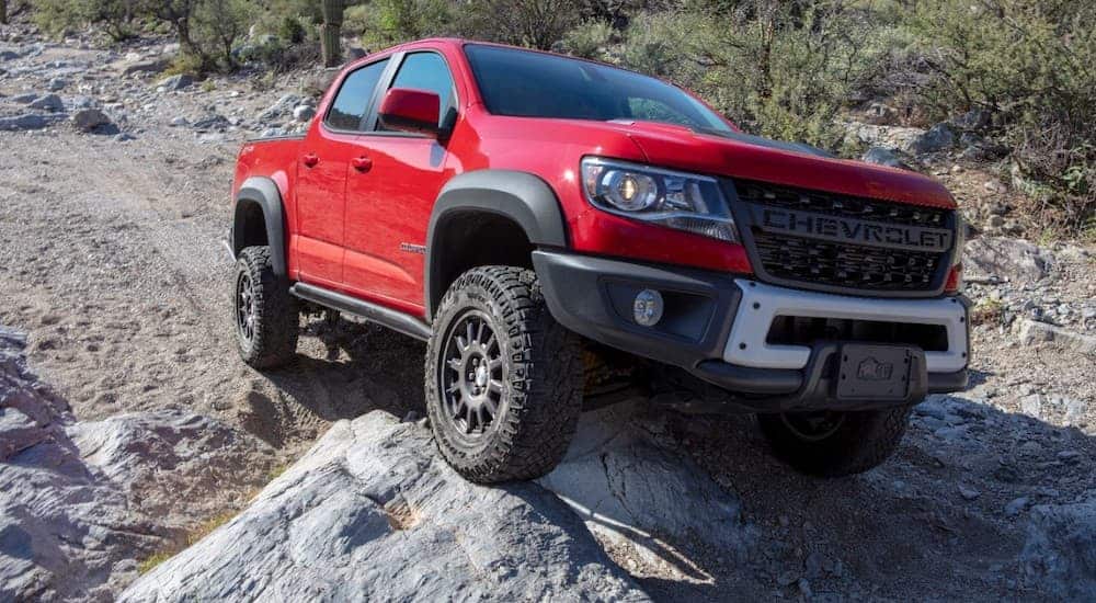 A red 2020 Chevy Colorado ZR2 Bison Rock is climbing a rock while off-roading.