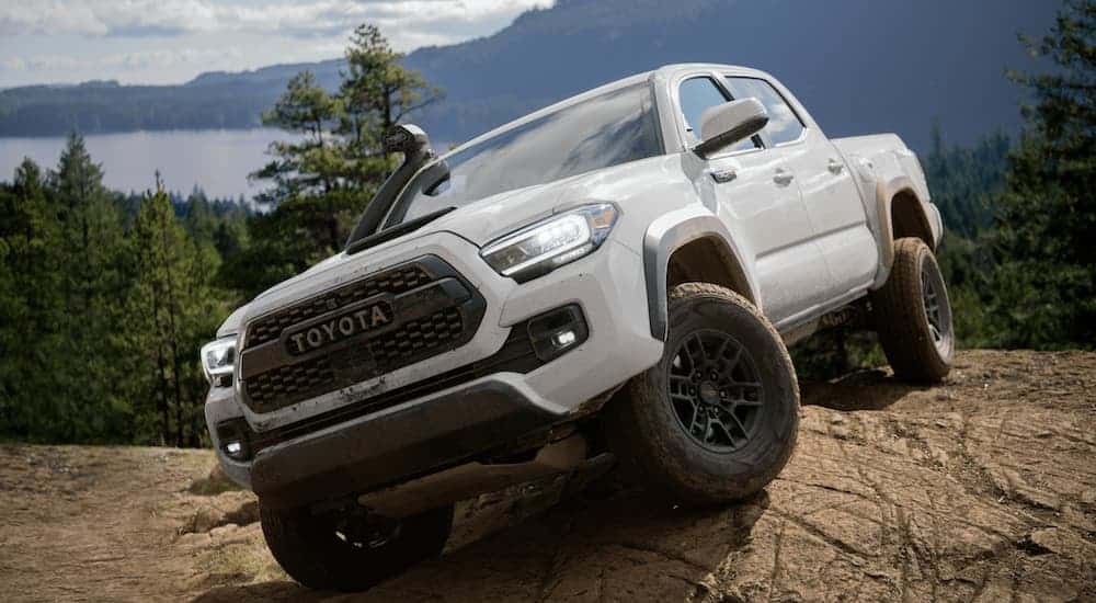 A white 2020 Toyota Tacoma TRD Pro is parked on a rock over looking a lake.
