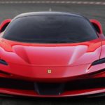 A red 2020 Ferrari SF90 Stradale is driving on a racetrack facing forward.