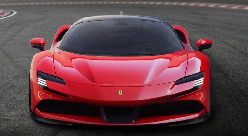 A red 2020 Ferrari SF90 Stradale is driving on a racetrack facing forward.