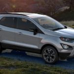 A silver 2019 Ford EcoSport, which is a popular option among Ford SUVs, is driving on a grass lined road.