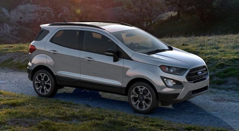 A silver 2019 Ford EcoSport, which is a popular option among Ford SUVs, is driving on a grass lined road.